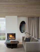 A natural wood ceiling, curving forms, and soft textiles combine to convey a sense of coziness in the sitting room.