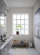 A white Vipp flagship pedal bin perches in the corner of the light-filled bathroom.