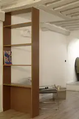 An in-built bookshelf doubles as a room divider, creating a restful nook without interrupting light or flow.