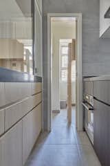Before: A slender sliding door at the end of the kitchen leads through to the family's live-in helper's room, featuring a loft bed over a desk and storage area.  Photo 5 of 23 in Before & After: Built-In Storage Unlocks the Potential of a Family’s Small Hong Kong Flat