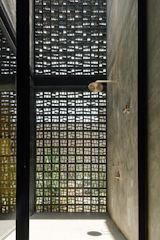 Concrete and breeze block walls surrounds a sunlit indoor shower.