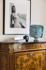 The apartment includes notable, rare pieces such as an 18th-century inlaid secretary desk purchased from Seguso in Paris, above which hangs a famous photo of Sophia Loren in Venice in 1955. The blue ceramic sculpture is a contemporary piece.