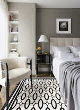 The guest bedroom is furnished in cool tones of gray and white with a graphic Stark carpet.