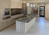 Kitchen with ten foot breakfast bar of Brazilian Quartzite, steam oven and induction cooktop.