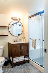 The upstairs bathroom layout was adjusted to allow for a large, walk-in shower lined with white subway tile. A marble-topped vanity with an oil-rubbed bronze faucet sits atop gray, hexagonal floor tiles.
