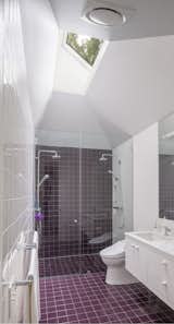 The maroon-tiled, walk-in shower has two showerheads and is well lit by a skylight from above.