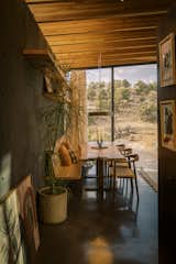 The dining area frames panoramic views to the northeast through expansive glass openings. Artwork by Andrew Alba. Custom table by Locus Studio.

