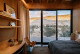 The guest bedroom frames desert views and morning light. Bed by Blu Dot. Wall lamps by Artemide.

