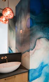 In the powder room, a Tom Dixon pendant dangles above a Ferguson Badeloft sink. Dreamy blue watercolor wallpaper from Black Crow Studios lines the walls.