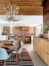 Jobe Corral Architects River Ranch house dining room and kitchen featuring rammed-earth wall and copper hood vent.