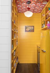 There are no upper cabinets in the kitchen, but a large walk-in pantry in the middle of the home—decked out in a cheery yellow paint and chicken-print wallpaper from Voutsa—provides ample storage. 