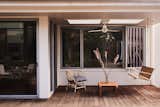 The deck is crafted from Brazilian hardwood. Here, a custom porch swing echoes the front porch in a more modernist way. A wicker Ikea chair offers another chic seating option. The ceiling fan on the porch was a must, according to Christina. “I’m from the South. I know that if we’re gonna sit on the porch, we’re gonna need a swing and a fan.”