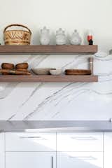
The kitchen backsplash is one solid piece of quartz, while the countertops are a blend of quartz and concrete. The floating shelves in the kitchen are all lit from underneath.