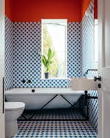 After: The visible structure that wraps the tub is a nod to the exposed trusses elsewhere in the home. Meanwhile, the blue-and-white checkerboard tiles and orange walls are a fun continuation of the cheery color palette found throughout the remodel.