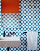 Orange paint and blue-and-white checkerboard tiles are a gleeful match in the bathroom.