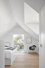 The only furniture in the bedroom is a bed and side chair. Light pours in through an angled skylight and the former hay-bale window that faces the street.&nbsp;