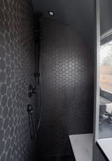 The all black bathroom is surprising (but stylish) in the compact space, tiled with two-inch rounds. The original plan, however, would have been even more unusual. "We wanted red grout as a nod to Darth Maul," laughs Kyle. That color concept lives on in the custom storage cabinet Schmitt designed for Kyle’s Dyson, with special red and black foam cutouts for the various vacuum pieces to be nestled in. 