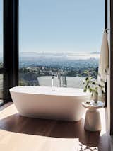 The bathroom features a stunning floor-to-ceiling window.