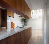Cabinets hang from the ceiling around the kitchen, helping defining the area without obstructing the natural light that flows throughout the building.