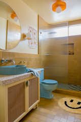 Yellow tiles cover the floors and wall of the upstairs bathroom, but on the shower floor, a retro blue-and-white checkerboard pattern ties into the powder-blue sink and toilet.
