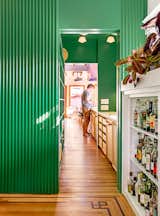 "I like that you can feel the old shapes of the house," says Lanigan, who intentionally let the trim and fireplace "run into" the green box. Dark wood detailing on the floor reveals the outlines of the home’s former rooms. 