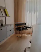 A vintage Wassily chair sits in the library by the soft, butter-colored curtains. 