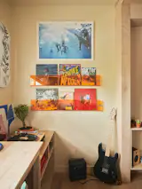 Orange shelves hold records and magazines, and add a pop of color to contrast the blue of the tiles and surf photography.