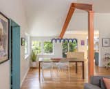 An exposed steel beam and column—painted in cheerful Benjamin Moore Pumpkin Patch—celebrates the structural intervention needed to open up the space. An Oblure Arch pendant in blue anchors the dining area.