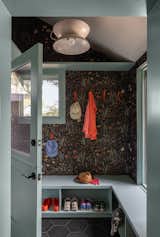 Custom teal cabinets by Kable Design Build provide storage in the new mudroom, while durable Bedrosians hexagon tiles in Kuroi Black cover the floor.