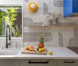 Jess arranged the Wow tiles into this hypnotic pattern for the backsplash. A Ferroluce BumBum sconce in yellow adds a punch of color to complement the bright-blue range hood. 