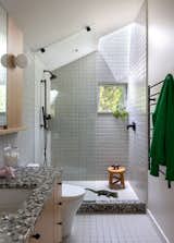 Fireclay’s Essentials tiles in Manzanita Satin cover the walls and floor, while Concrete Collaborative’s Pacifica slab in Mint Retro Mix accents the countertops and shower. Kohler Components fixtures in black provide a bold contrast against the custom, rift-sawn white oak vanity.