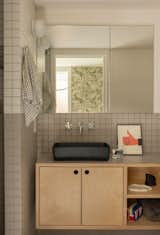 Daltile Keystone tiles in Arctic White and Desert Gray create a duotone effect in the ADU bathroom. A Concretti Reno sink in Kale sits atop a custom Kable Design Build vanity in birch plywood with a Pionite Stonedust laminate countertop. 