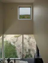 Expansive glazing frames views of pastures and distant hills, as well as the rocky terrain right outside the window. 