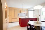A scalloped red lacquered MDF island adds sculptural presence to the compact kitchen, paired with Cambria Minnesota Snow countertops in matte finish—chosen after visiting countless showrooms.