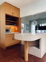 Custom pulls integrated into white oak cabinetry add tactile detail while maintaining clean lines. The dishwasher and refrigerator hide behind matching panels.