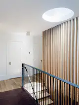 A new skylight and cedar slat light well pull sunshine deep into the formerly dark kitchen, transforming how the family moves through the space.