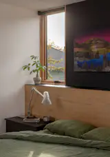 A headboard wrapped in leftover Madera oak flooring demonstrate creative material reuse. Artwork by Ryan Dobrowski hangs above the bed.