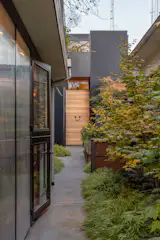 The lush entry courtyard features native plants in custom steel planters by Bucktide General Contractors. RBW Dimple exterior porch lights illuminate the entryway.