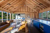 The cathedral-ceilinged great room spans 20-by-24 feet with 14-foot ceilings—impossibly grand for a 1,050-square-foot house. The kitchen island doubles as stair railing, eliminating visual interruptions between living, dining and cooking zones.