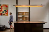 Stainless steel countertops top the kitchen island beneath a custom pendant light designed by Jeff Shaw of Intersect Studio and fabricated by Marc—one of dozens of steel elements throughout the suite.