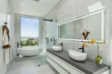 The primary suite includes a marble-clad spa bath featuring a soaking tub with water views.