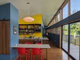 The kitchen is simple and efficient: appliance costs were kept low, and the dishwasher eliminated by building in a cupboard that doubles as a dish rack. The corridor leading back to the bedrooms follows the roof line to dramatic effect. The vibrant colors provide joy and contrast to the bright daylight.