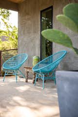 Blue papasan chairs add a pop of color to a sheltered patio.&nbsp;