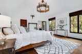Bedroom, Pendant Lighting, Bed, and Medium Hardwood Floor Large Master Ensuite with canted ceilings, vintage chandelier, 2 walk-in closets, and original bath  Photo 13 of 30 in Charli XCX's Hollywood Hills Tudor Estate by Christine Hameline