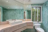 Green tiles and a pale wood vanity echo the landscape.&nbsp;