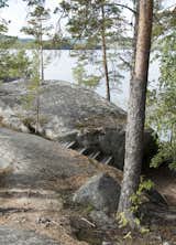 The Experimental House overlooks the rocky shore of Lake Päijänne. Here, the wooden steps leading up to the dwelling are shown nestling among the boulders as though part of the landscape.