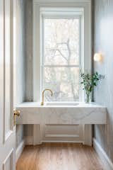 A powder room was designed at the parlor level, with a contemporary and minimal feeling. The wall-to-wall marble sink integrates with the window, bringing the outdoor view inside.