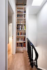 The hallway on the second level features a bookcase that frames the space, making the hatch to access the room an opportunity for a functional and decorative element.