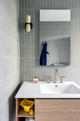The kids bathroom is characterized by sage color tiles and a wood vanity, for a playful and minimal design.