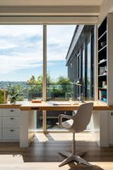 In the office, a meticulously engineered bespoke standing desk seamlessly integrates into the custom millwork, providing an attractive view from the exterior terrace. It is designed to balance aesthetics while ensuring functional operability, creating a comfortable workspace.
